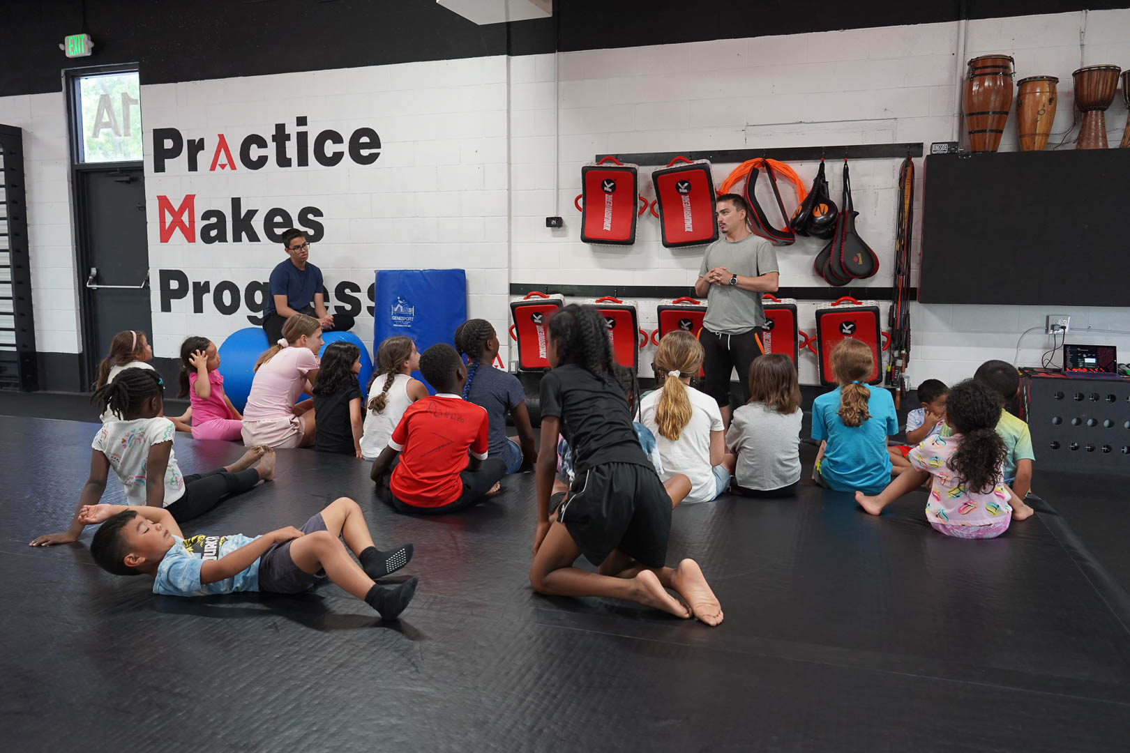 A coach speaking with campers on the mats at Zero Gravity